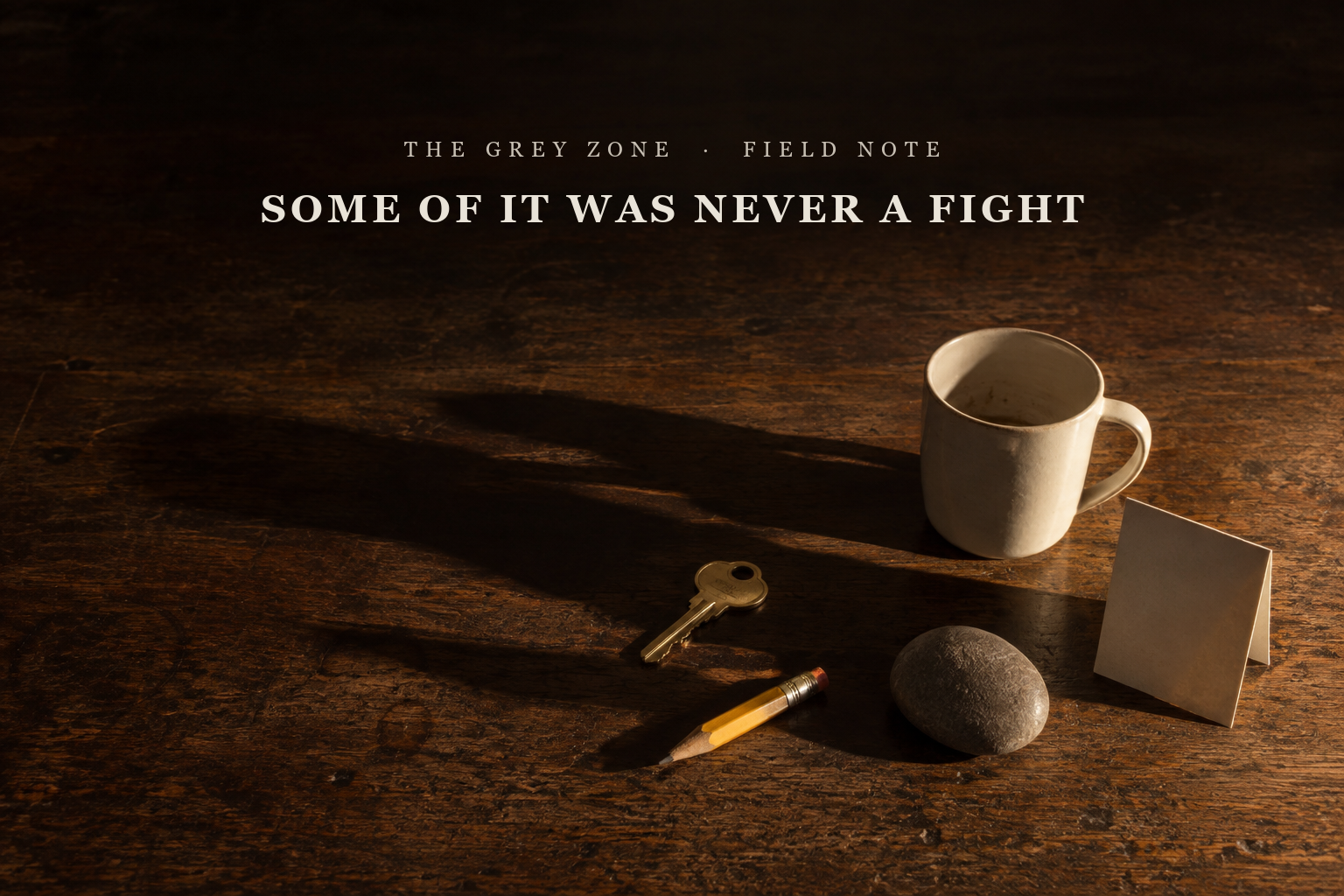 Five unrelated objects set down close together on a dark wooden table in low raking light, a mug, a key, a pencil, a stone and a folded card, their long shadows running into one another to form a single dark shape while the objects themselves do not touch. The article title is set into the quiet space above.