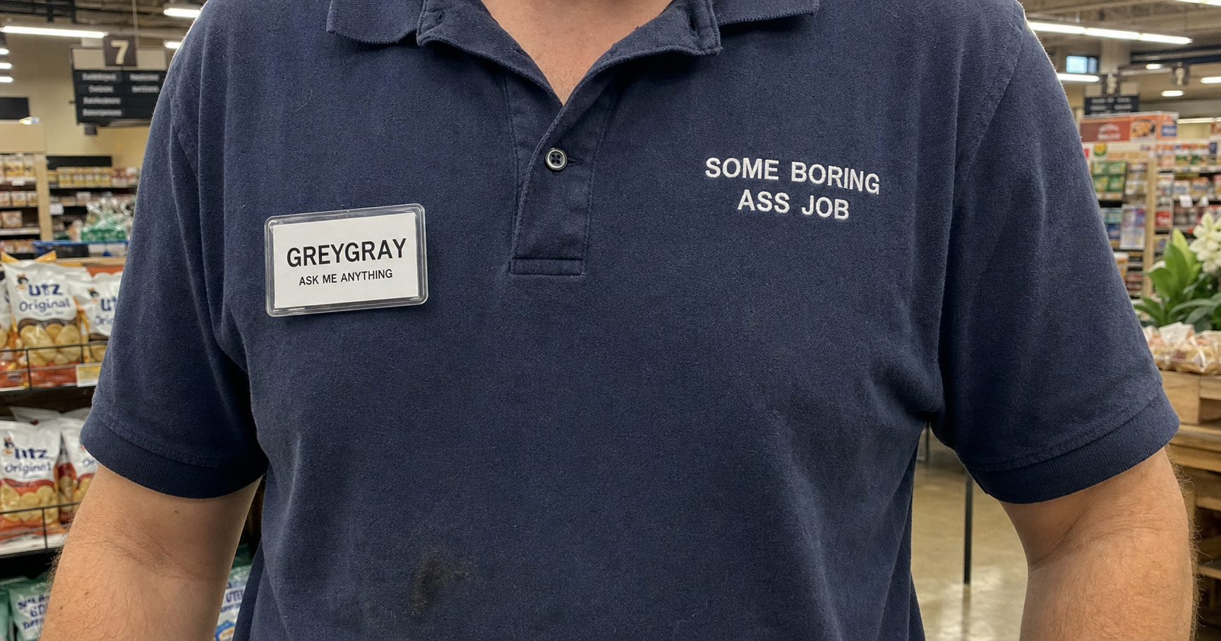 Greygray nametag on a navy polo embroidered 'Some Boring Ass Job,' standing in aisle 7 of a grocery store.